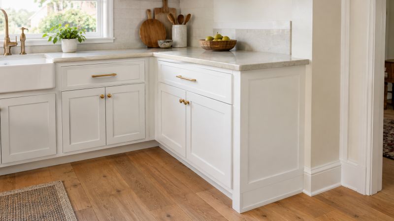 White kitchen cabinets beside a light countertop and warm oak flooring